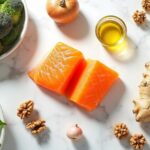 Flat lay com 10 alimentos anti-inflamatórios: peixe gordo, cúrcuma, gengibre, nozes, azeite de oliva, brócolis, espinafre, frutas vermelhas, alho, cebola e abacate